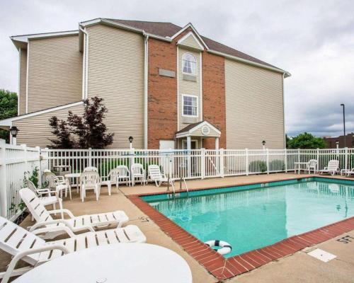 a swimming pool with white chairs and a house at Quality Inn & Suites in Belinda City