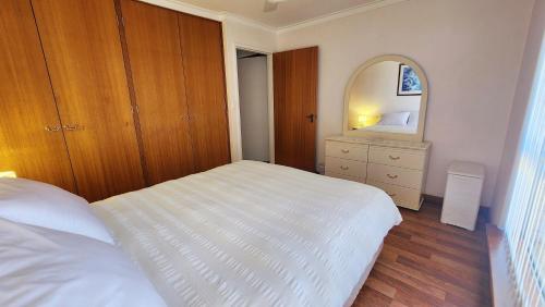 une chambre avec un lit blanc et un miroir dans l'établissement Hello House, à Safety Bay