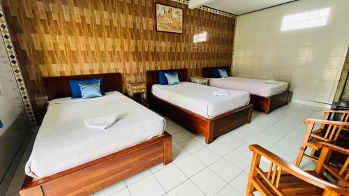 a room with two beds and a chair in it at Hotel Segara in Kubupenlokan