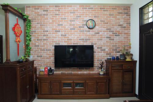 a living room with a tv on a brick wall at Ancient Official Road Homestay in Jinhu