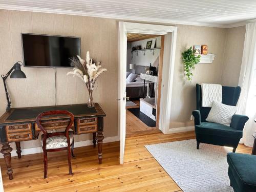 Elle comprend un salon avec un bureau et une télévision murale. dans l'établissement Country Escape, Cozy Village Cottage, à Falun