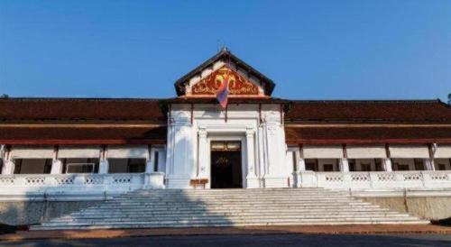 a building with stairs and a door with a flag at Sysomphone G.H in Luang Prabang
