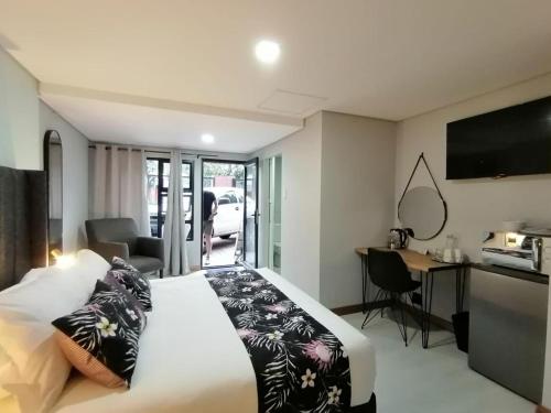 a bedroom with a bed and a desk and a television at The Chameleon in Centurion