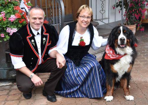 a man and a woman kneeling next to a dog at Hotel Gletschergarten in Grindelwald