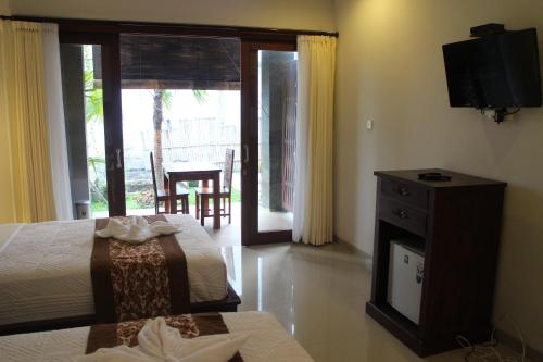 a bedroom with a bed and a television and a balcony at Betutu Bali Villas in Ubud