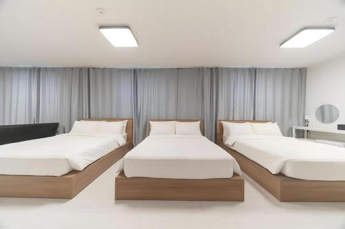 two beds in a hotel room with white sheets at La Famille in Chosan-ni