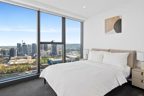 een slaapkamer met een wit bed en grote ramen bij Festival Towers Brisbane in Brisbane
