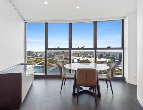 een eetkamer met een tafel en stoelen en grote ramen bij Festival Towers Brisbane in Brisbane