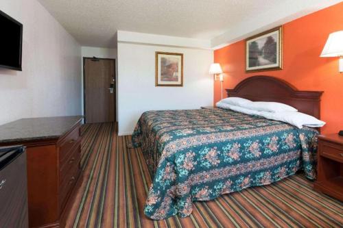 a hotel room with a bed and a flat screen tv at Knights Inn Ferguson MO in Castle Point