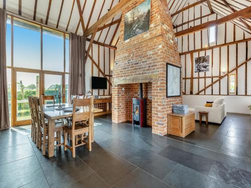 a dining room with a brick fireplace in a house at Liston Hall Barn in Gosfield