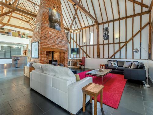 a living room with a white couch and a brick fireplace at Liston Hall Barn in Gosfield