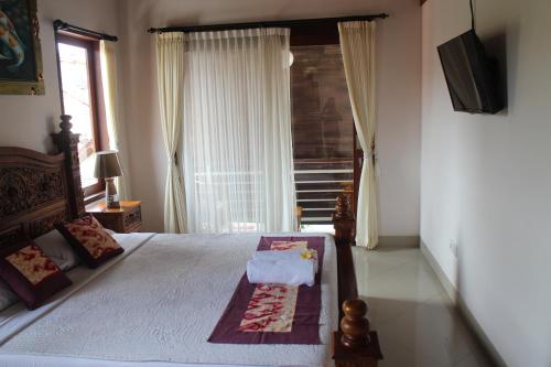 a bedroom with a bed with a television and a window at Betutu Bali Villas in Ubud