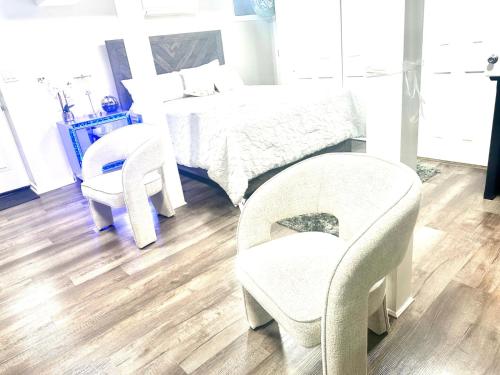 a bedroom with a bed and two chairs and a table at Belmont Lux Escape - Walkable Studio 19 Miles to Manhattan in Elmont
