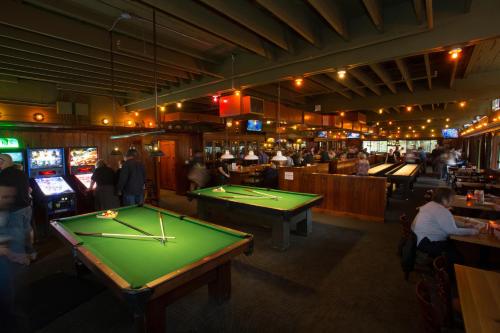 a pool table in a bar with people playing video games at McMenamins Anderson School in Bothell