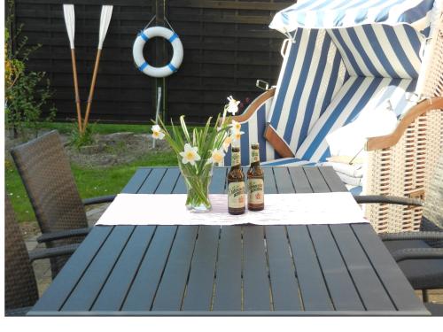 a picnic table with two bottles of beer and a vase of flowers at Nordseejuwel in Friedrichskoog-Spitz