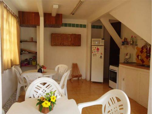 a kitchen with a table and white chairs in a kitchen at Território da Paz Pousada na Praia da Ferrugem in Garopaba
