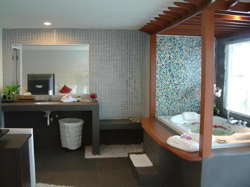 a bathroom with a tub and a sink and a mirror at Hua Hin Avenue Hotel in Hua Hin