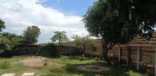 a fence with a tree in a yard at Mekong Sedone Hostel Neva Paris in Pakse
