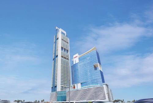 a tall building in front of a blue sky at Luxery Hotel Apartment l Novotel Residence l JVT in Dubai