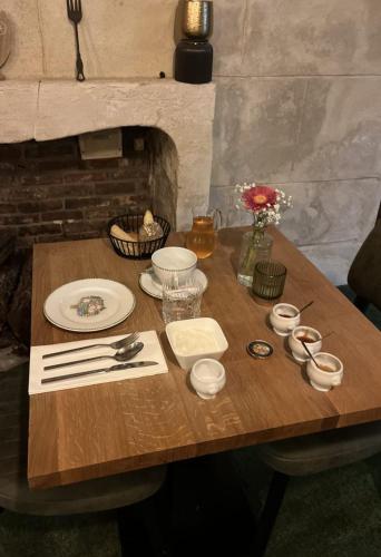 a wooden table with plates and utensils on it at L'Authentique in Beaumont-le-Roger