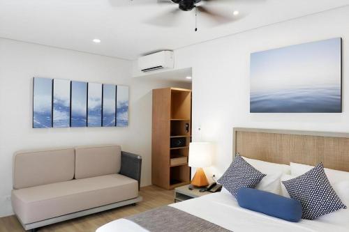 een slaapkamer met een bed met een bank en een stoel bij HUNI LIO in El Nido Airport