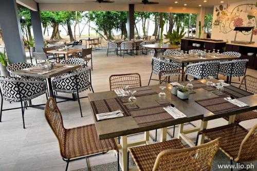 een leeg restaurant met tafels, stoelen en een tafelblad bij HUNI LIO in El Nido Airport