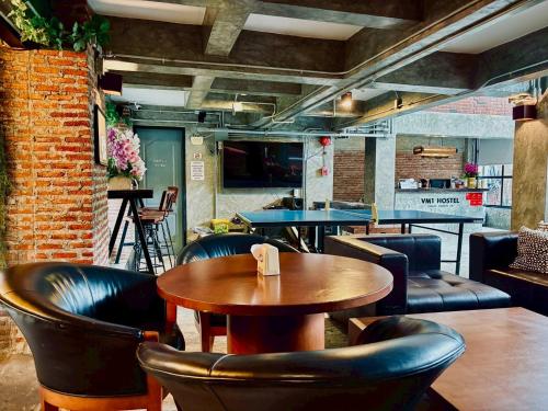 a restaurant with a wooden table and leather chairs at Sukhum Victorymonument-Ari in Bangkok