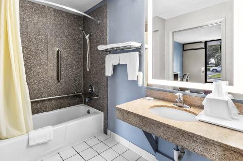 a bathroom with a sink and a tub and a mirror at Econo Lodge Goose Creek - Charleston North in Goose Creek
