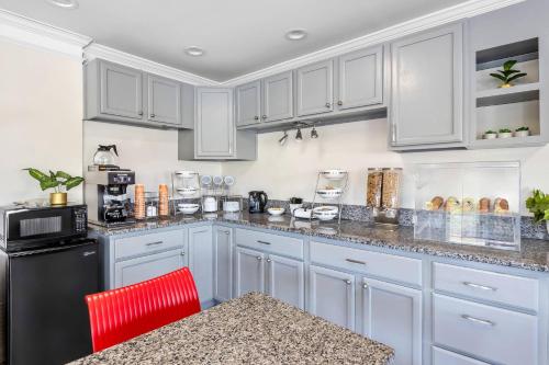 a kitchen with white cabinets and a red chair at Econo Lodge Goose Creek - Charleston North in Goose Creek