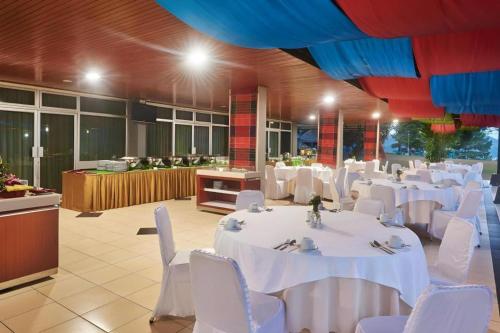 a banquet hall with white tables and white chairs at Patra Comfort Parapat in Parapat