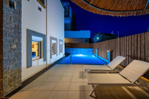 a patio with chairs and a swimming pool at night at Bougan Villa in Lartos