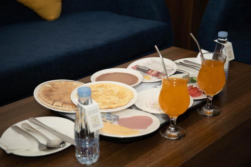 una mesa con platos de comida y vasos de jugo de naranja en فندق اهلا Hola Hotel, en Al Jubail