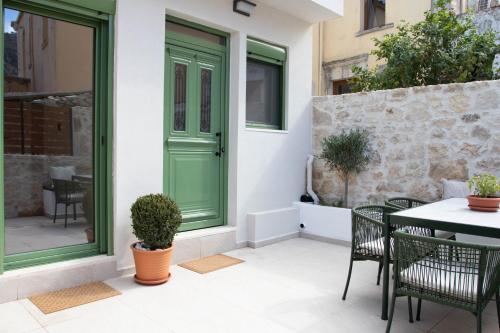 eine grüne Tür auf einem Haus mit einem Tisch und Stühlen in der Unterkunft Alexandra Heritage Μaison in Archanes