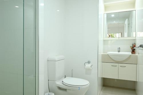 a white bathroom with a toilet and a sink at St Tropez 8 - Waterfront Retreat with Rooftop Spa & Sauna in Noosa Heads