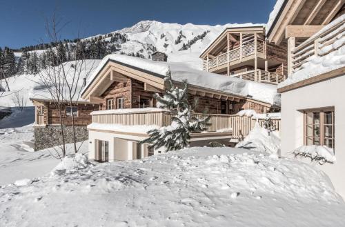 una casa en la nieve con una montaña en el fondo en Aadla Walser-Chalets mit privater Sauna, Hotpot und Hotelservice, en Schröcken