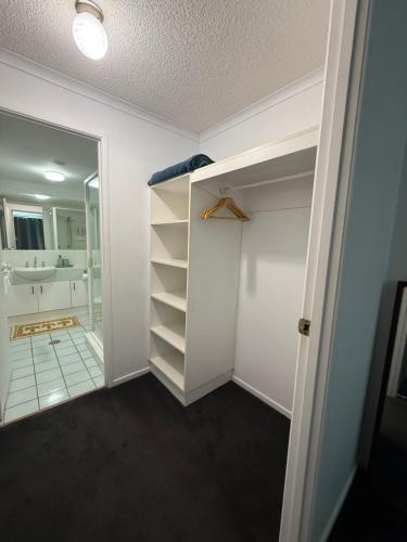a bathroom with a walk in closet and a mirror at Absolute Beachfront Apartment, Kawana Beach Escape in Buddina