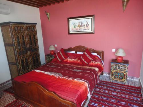 a bedroom with a bed with a red wall at Dar Yanis in Rabat
