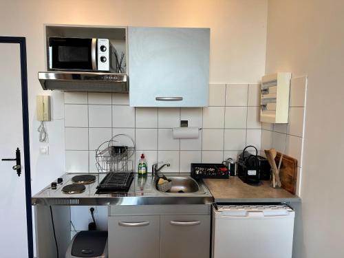 a small kitchen with a sink and a microwave at Le studio Vintage du centre ville - Proche coeur historique in Bergerac