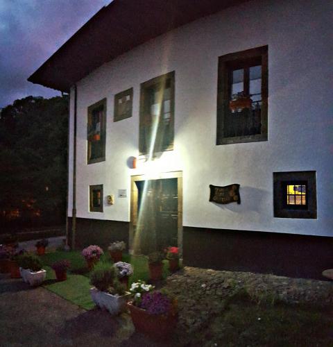 a white house with potted plants and windows at night at Hotel Rural Palacio de Galceran in Sotiello