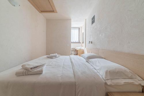 a white bedroom with a large bed with towels on it at Casa Scola in Falcade