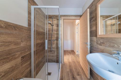 a bathroom with a glass shower and a sink at Casa Scola in Falcade