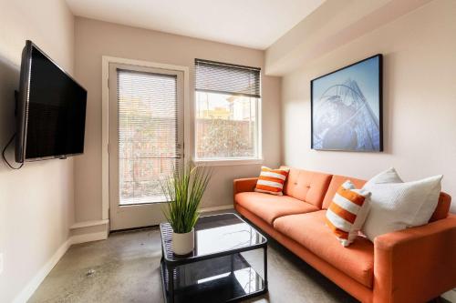 a living room with an orange couch and two windows at Stay Portland - Bright Studio Apartment - Food Carts & Local Shops in Portland