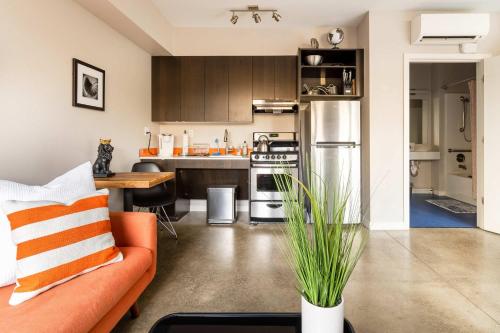 a living room with an orange couch and a kitchen at Stay Portland - Bright Studio Apartment - Food Carts & Local Shops in Portland