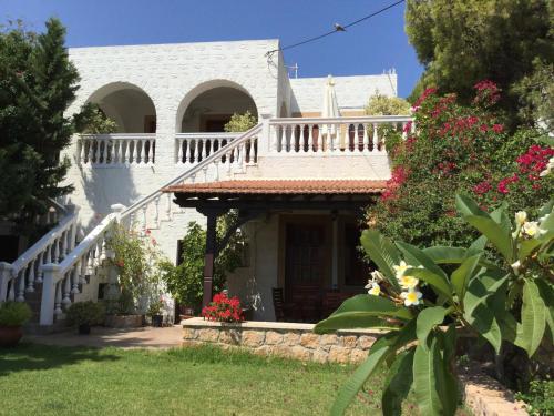 a white house with a staircase and flowers at Studios Irene in Skala