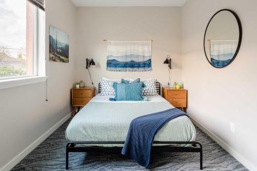 a bedroom with a bed with blue pillows and a mirror at Stay Portland - The Mid-Century Cabin in Portland - Thrift & Eat in Portland