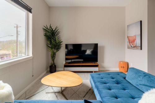 a living room with a blue couch and a tv at Stay Portland - Retro Modern 2-Bedroom with 90 WalkScore in Portland