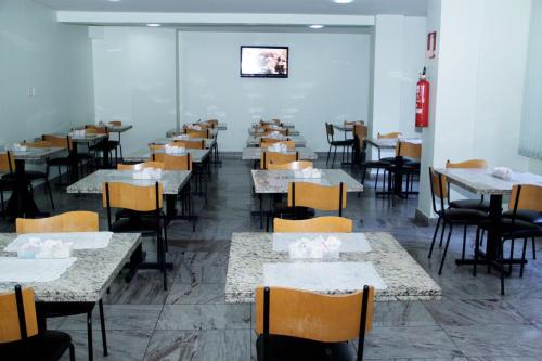 un comedor lleno de mesas y sillas en Estoril Hotel en Belo Horizonte