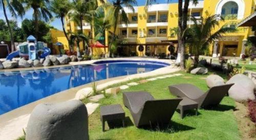 a resort with a pool with chairs and a building at Country Village Hotel in Carmen