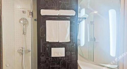 a bathroom with a shower and a towel rack with towels at Ibis Ya An Langqiao in Shaping