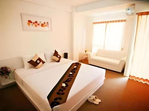 a white bedroom with a large white bed and a couch at The Residence Prachinburi in Si Maha Phot
